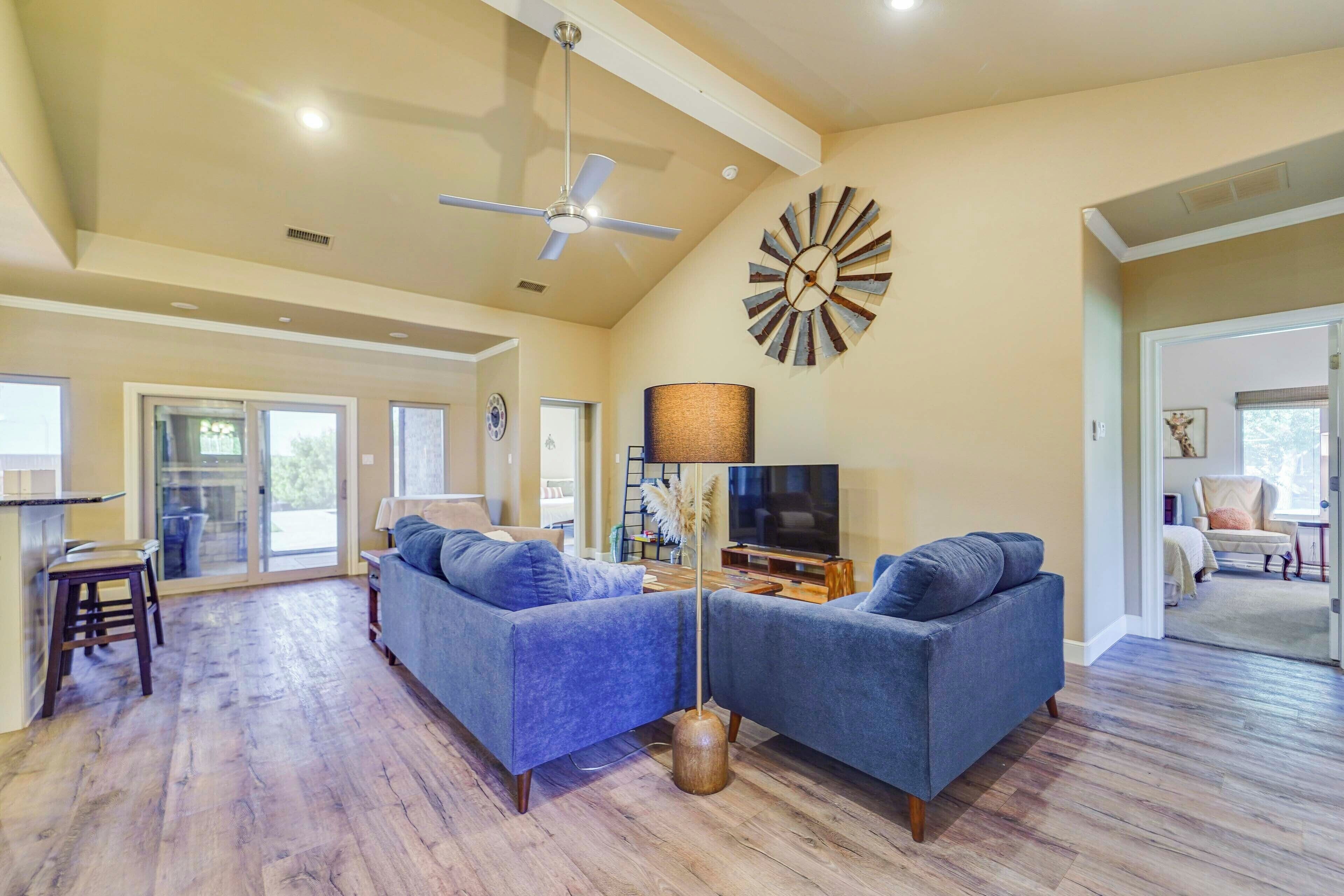 A spacious living room with a ceiling fan, a large clock, and a TV.