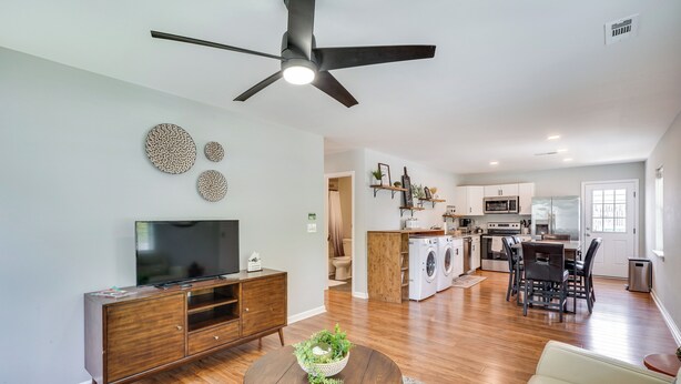 A modern living room with a flat-screen TV, wooden entertainment center, and a round coffee table with a bowl of green plants. - 2 Mi to Dtwn Durham: Home Near Universities (Durham)