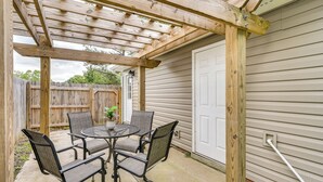 A covered patio with a wooden pergola, a round table with four chairs, and a white door in the background. - 2 Mi to Dtwn Durham: Home Near Universities (Durham)
