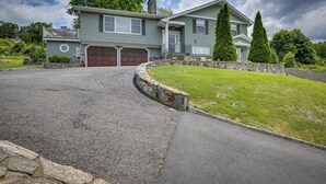 A two-story house with a front garage, a stone retaining wall, and a well-maintained lawn. - New Fairfield Vacation Rental w/ Lake Views! (New Fairfield)