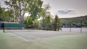 An outdoor tennis court with a net, surrounded by a fence and trees. - New Fairfield Vacation Rental w/ Lake Views! (New Fairfield)