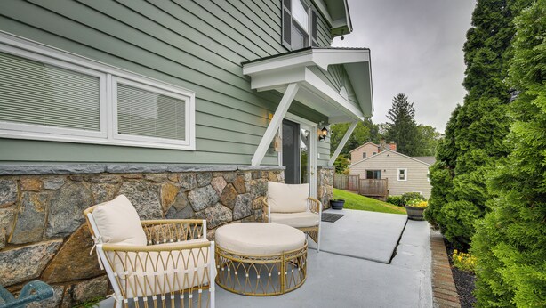A house with a stone foundation, a porch with wicker furniture, and a well-maintained garden. - New Fairfield Vacation Rental w/ Lake Views! (New Fairfield)