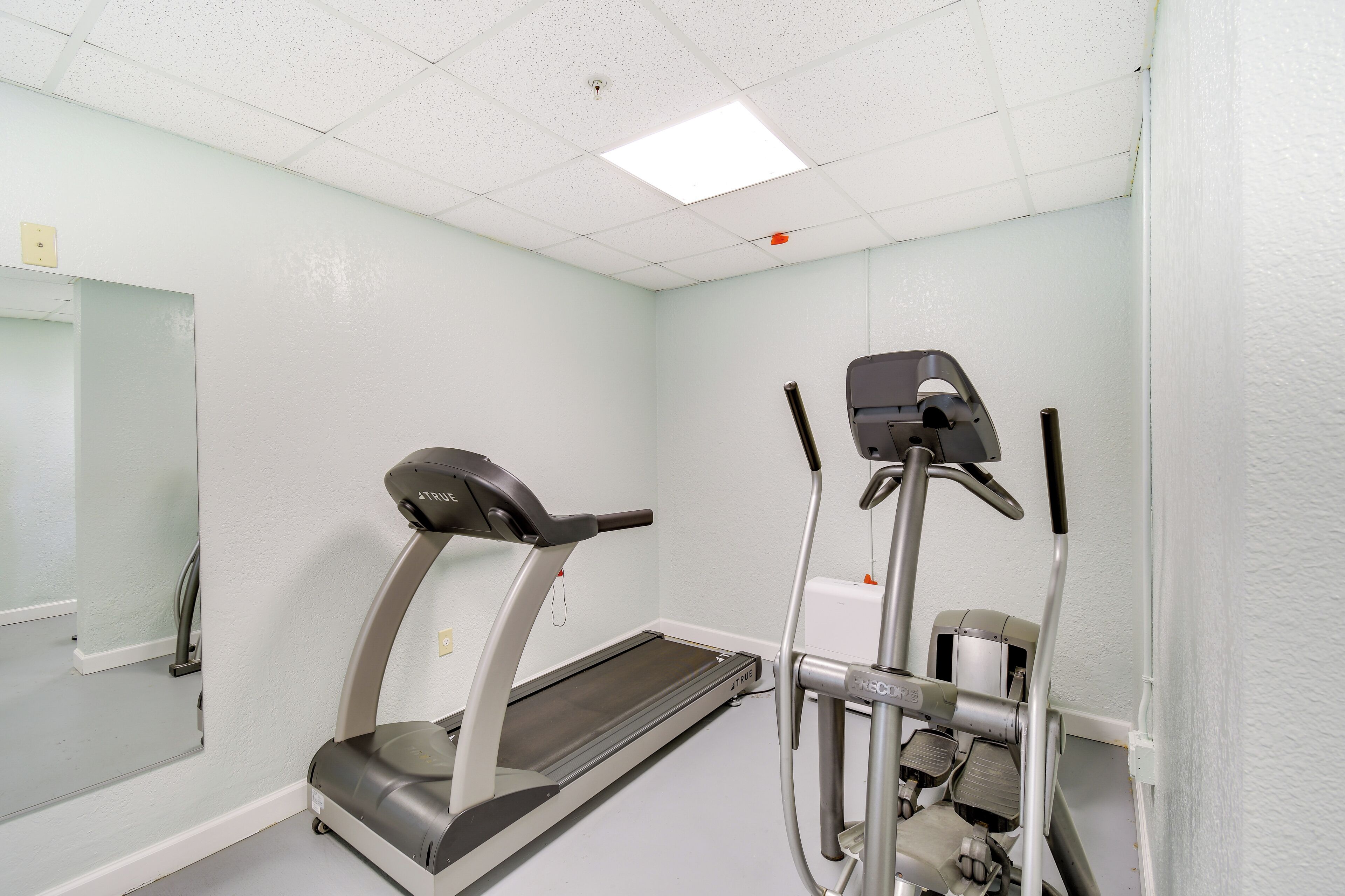 A fitness room with a treadmill, elliptical, and stationary bike.