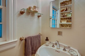 A bathroom with a white sink, two faucets, a glass soap dispenser, and a mirror above the sink. - Spacious Durham Apartment Near Downtown (Durham)