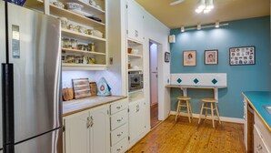 A kitchen with white cabinets, a stainless steel refrigerator, wooden flooring, and a blue wall with framed photos. - Spacious Durham Apartment Near Downtown (Durham)