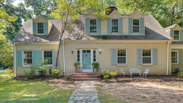 A two-story house with a stone pathway leading to the front door, surrounded by a well-maintained lawn and potted plants. - Spacious Durham Apartment Near Downtown (Durham)