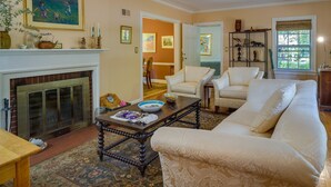A living room with a fireplace, a sofa, a coffee table, and a dining table. - Spacious Durham Apartment Near Downtown (Durham)