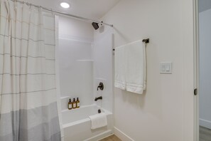 A bathroom with a shower, a bathtub, and a towel rack.
