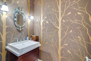 Une salle de bain avec un lavabo blanc, un miroir et des luminaires fixés au mur.