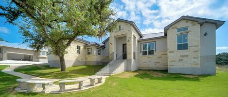 A modern two-story house with a stone facade, a covered driveway, and a well-maintained lawn.