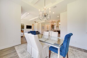 A modern dining area with a glass table, white upholstered chairs, and a blue accent chair. - 'cascada at Canyon Lake' ~ 1 Mi to Wedding Venues! (Spring Branch)