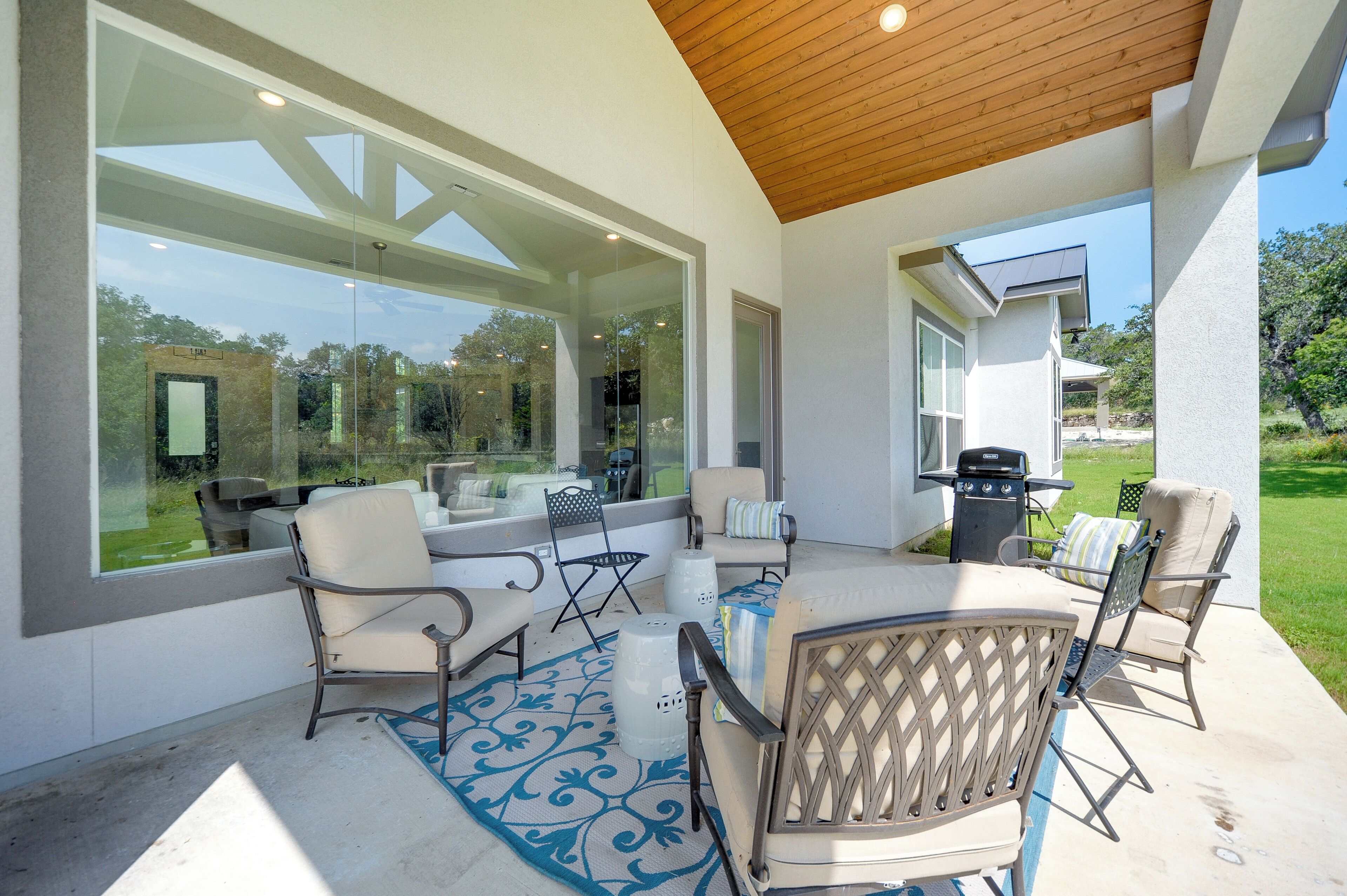 An outdoor patio with a table and chairs, a grill, and a view of the surrounding landscape.