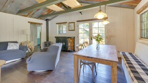 A rustic interior with wooden floors, a dining table, a sofa, and a fireplace. - Farmhouse-chic Carpinteria Cottage w/ Pool Access (Carpinteria)