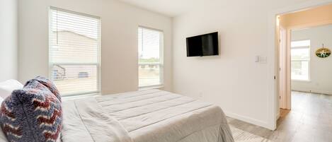 Un dormitorio con cama, ventilador de techo, televisor y ventana.