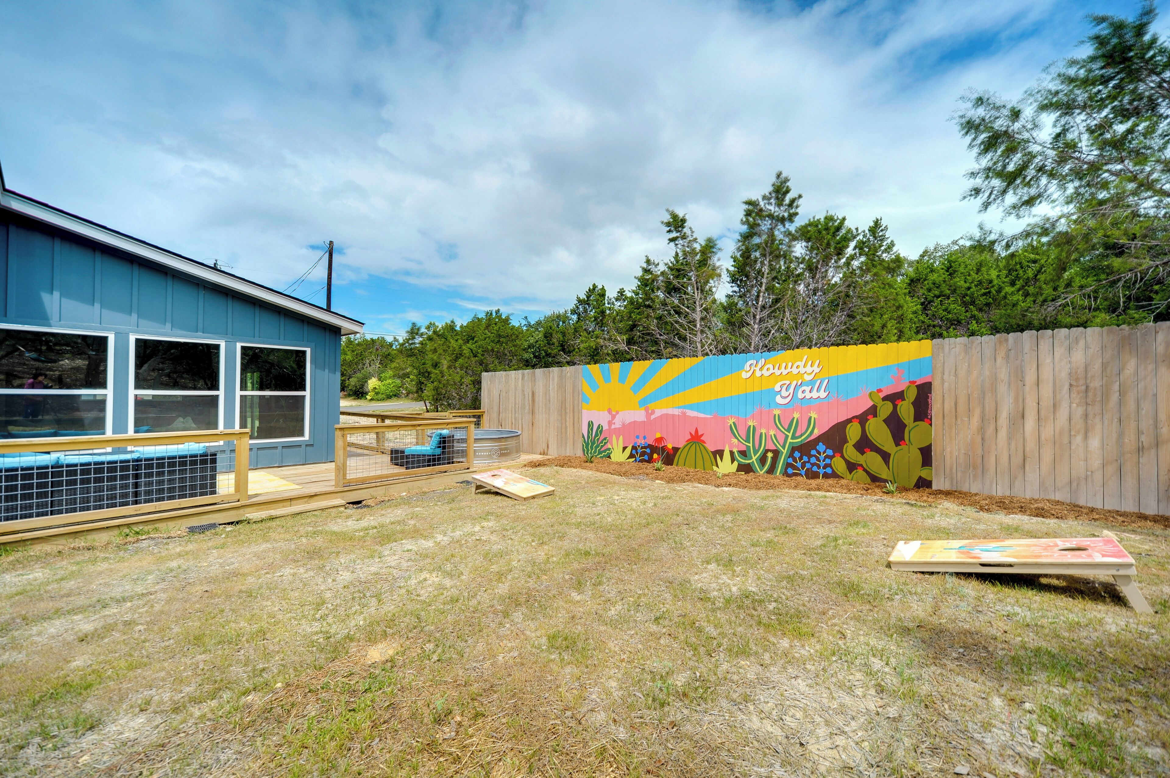 A building with a blue exterior and a mural on the adjacent wall depicting a desert scene with cacti and a sun.
