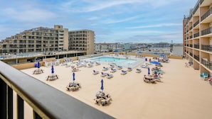 A rooftop pool area with lounge chairs and umbrellas, surrounded by buildings. - Beachfront Fourth-floor Condo w/ Community Pool! (North Wildwood)