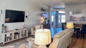 A spacious living room with a large flat-screen TV, comfortable seating, a wooden entertainment unit, and a view into the dining area. - Private Lanai & Pool Access: Home in the Villages! (The Villages)