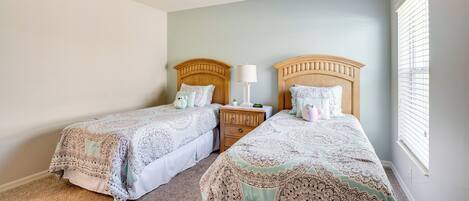 A bedroom with two beds, a ceiling fan, and a window with blinds.
