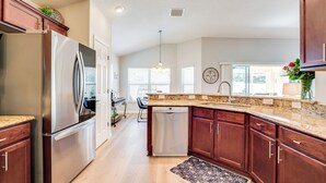 A modern kitchen with stainless steel appliances, wooden cabinets, granite countertops, and a central island. - Private Lanai & Pool Access: Home in the Villages! (The Villages)