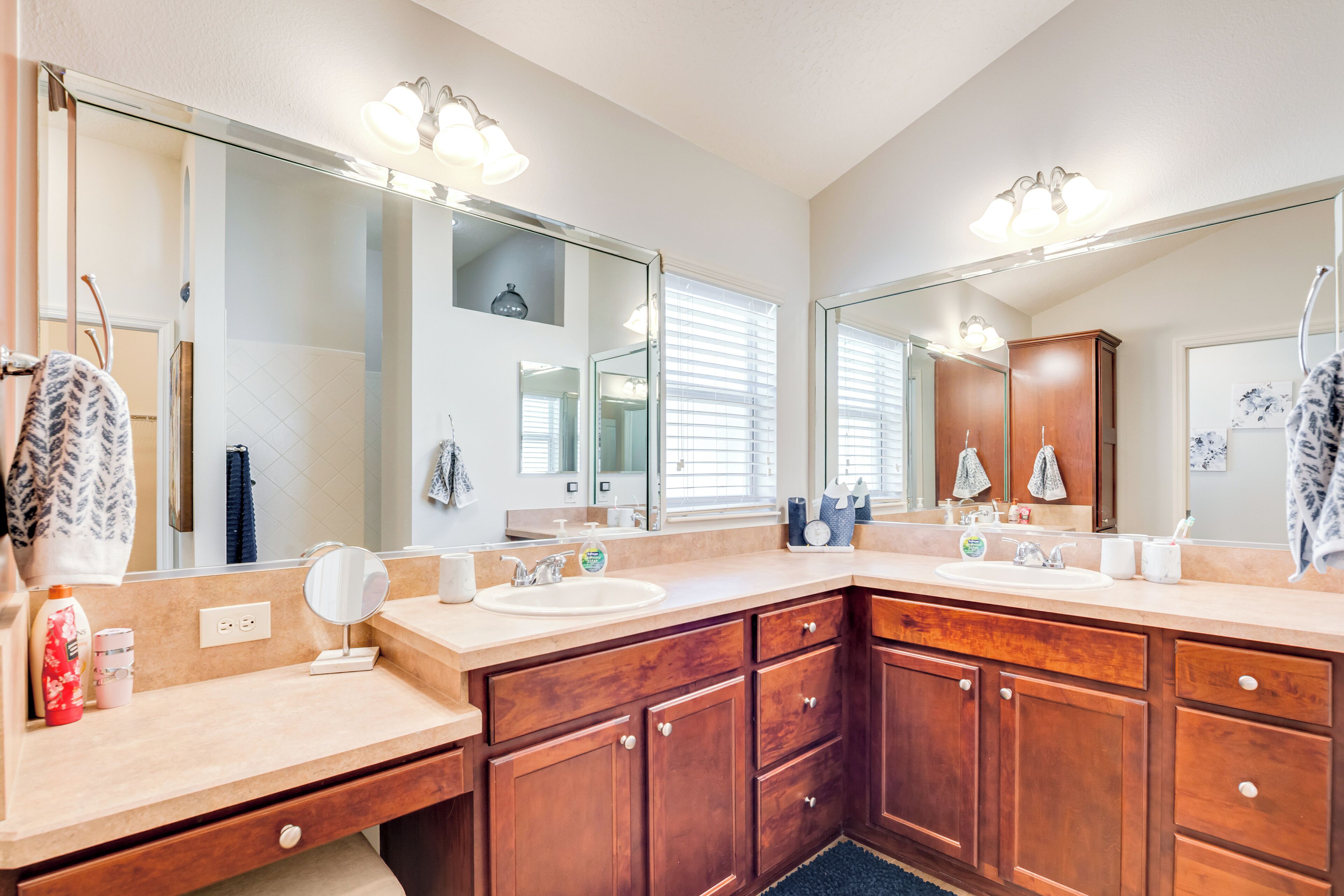 A bathroom with two sinks, wooden cabinets, a large mirror, and a towel rack.