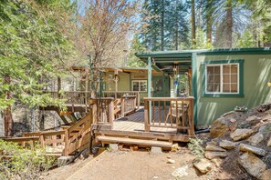 Un chalet rustique doté d’une terrasse en bois, d’un porche abrité et d’un petit espace extérieur aménagé pour s’asseoir.
