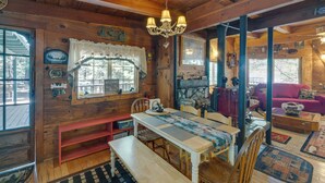 L’intérieur d’un chalet chaleureux, avec une table à manger en bois, des bancs, un lustre et un canapé rouge.