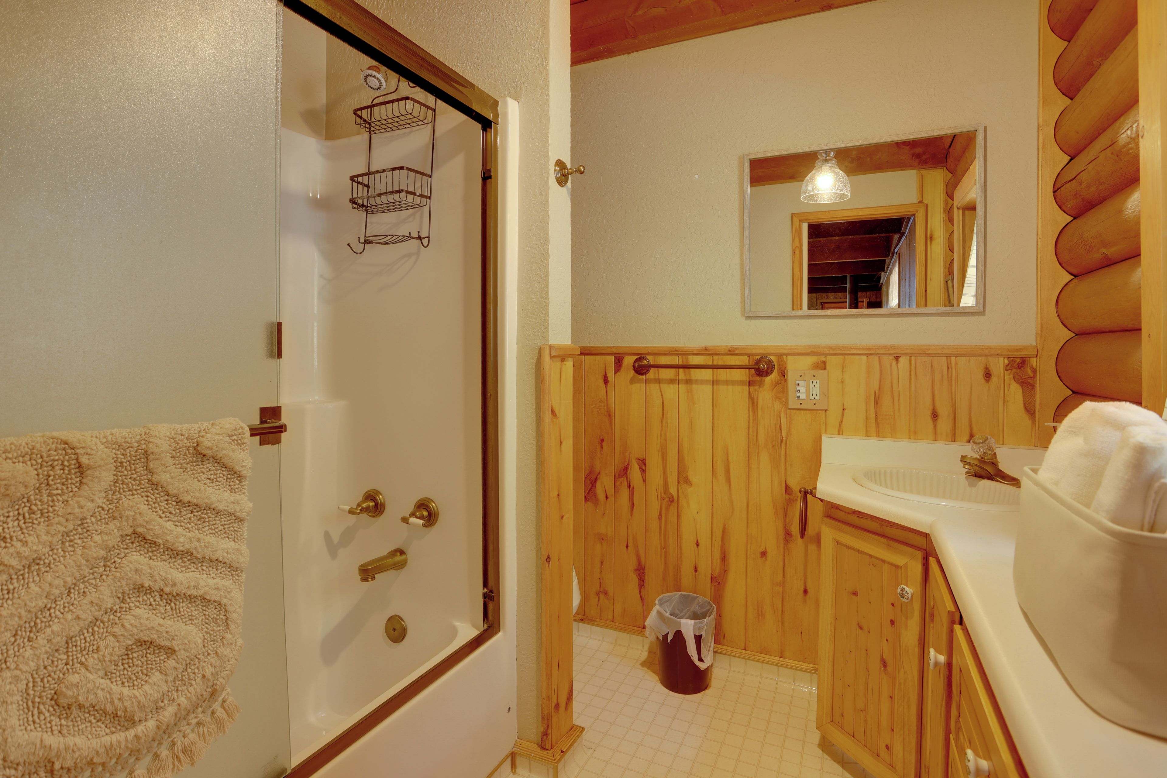 A bathroom with wooden walls, a white bathtub, a wooden sink, and a mirror above the sink.