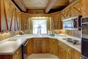 Una cocina compacta con armarios de madera, un lavamanos, un microondas y una estufa.