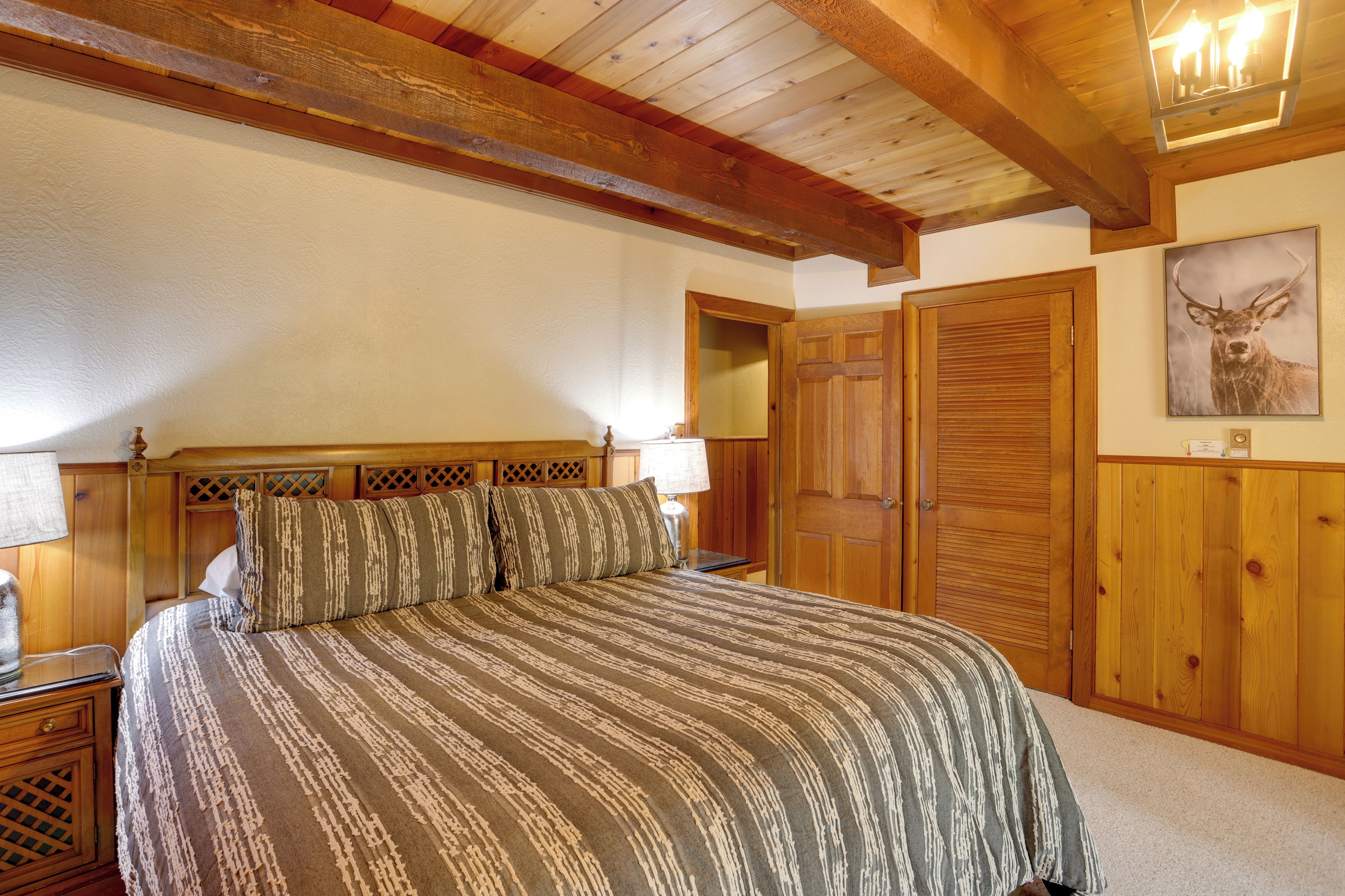A bedroom with a large bed, wooden headboard, and a wooden door with a mirror.