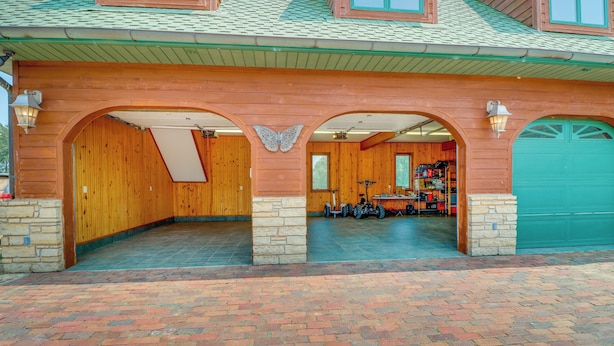 Un edificio in legno con un portico, colonne in pietra e un garage.