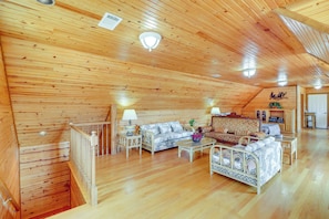 A spacious wooden interior with a high ceiling, a sofa set, a dining table, and a small kitchen area. - Hike & Fish: Studio w/ Pool Access in Shirley! (Shirley)