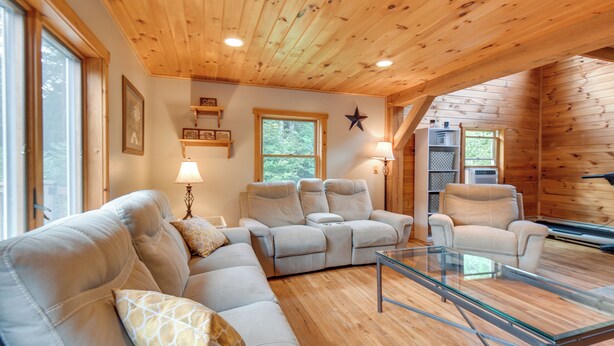 A cozy living room with a sectional sofa, a glass coffee table, and a fireplace. - Meredith Home w/ Deck: 6 Mi to Lake Winnipesaukee! (Meredith)