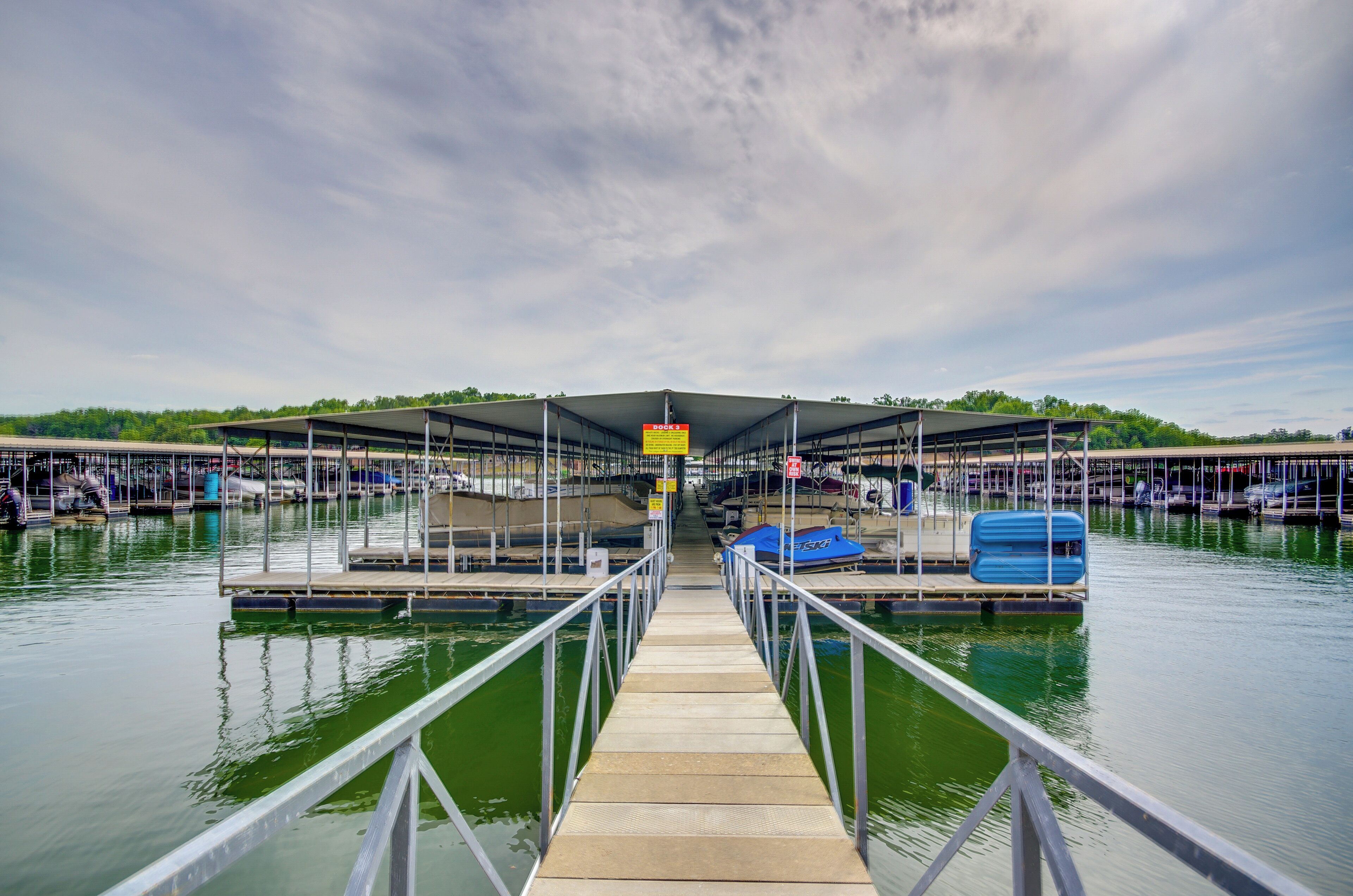 A marina with a covered dock, boats, and a clear sky.
