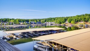 A marina with docked boats, covered seating areas, and a backdrop of lush green hills.
