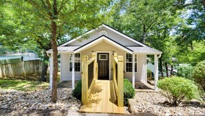 A small house with a porch and a wooden deck leading to the front door.