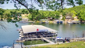 A docked boat rental facility with a covered area, a boat ramp, and a view of the lake and surrounding greenery.
