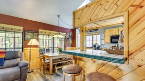 A cozy cabin interior with a dining area, wooden furniture, and a kitchen. - Central Big Bear Lake Retreat w/ Private Hot Tub! (Big Bear Lake)
