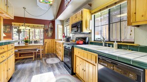 A kitchen with wooden cabinets, a stove, a microwave, and a sink. - Central Big Bear Lake Retreat w/ Private Hot Tub! (Big Bear Lake)