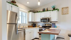 Una cocina moderna con armarios blancos, electrodomésticos de acero inoxidable y una isla central.