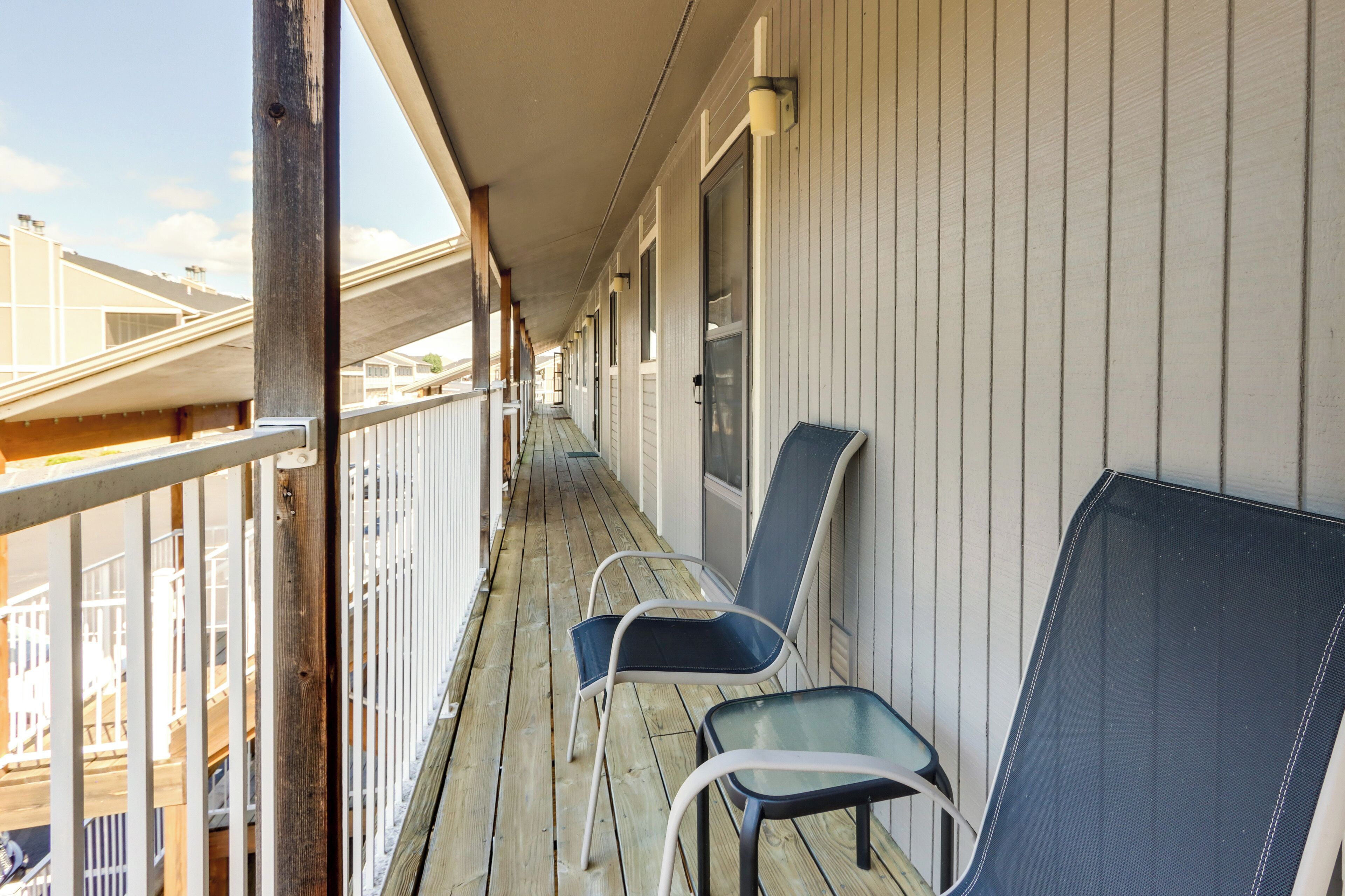 A wooden balcony with two chairs and a table, overlooking a residential area.