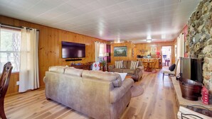 Una sala de estar acogedora con un sofá de cuero grande, suelo de madera, un televisor de pantalla plana y una pared de piedra.