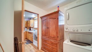 Una cocina compacta con armarios de madera, horno empotrado y zona de lavandería a la vista.