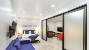 Ein modernes Hotelzimmer mit einem großen Bett, einem Sofa, einem Schreibtisch und einem Fernseher.