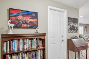 A room with a bookshelf, a door, and two paintings. - Secret Garden Retreat Private Patio Kitchen (American Fork)