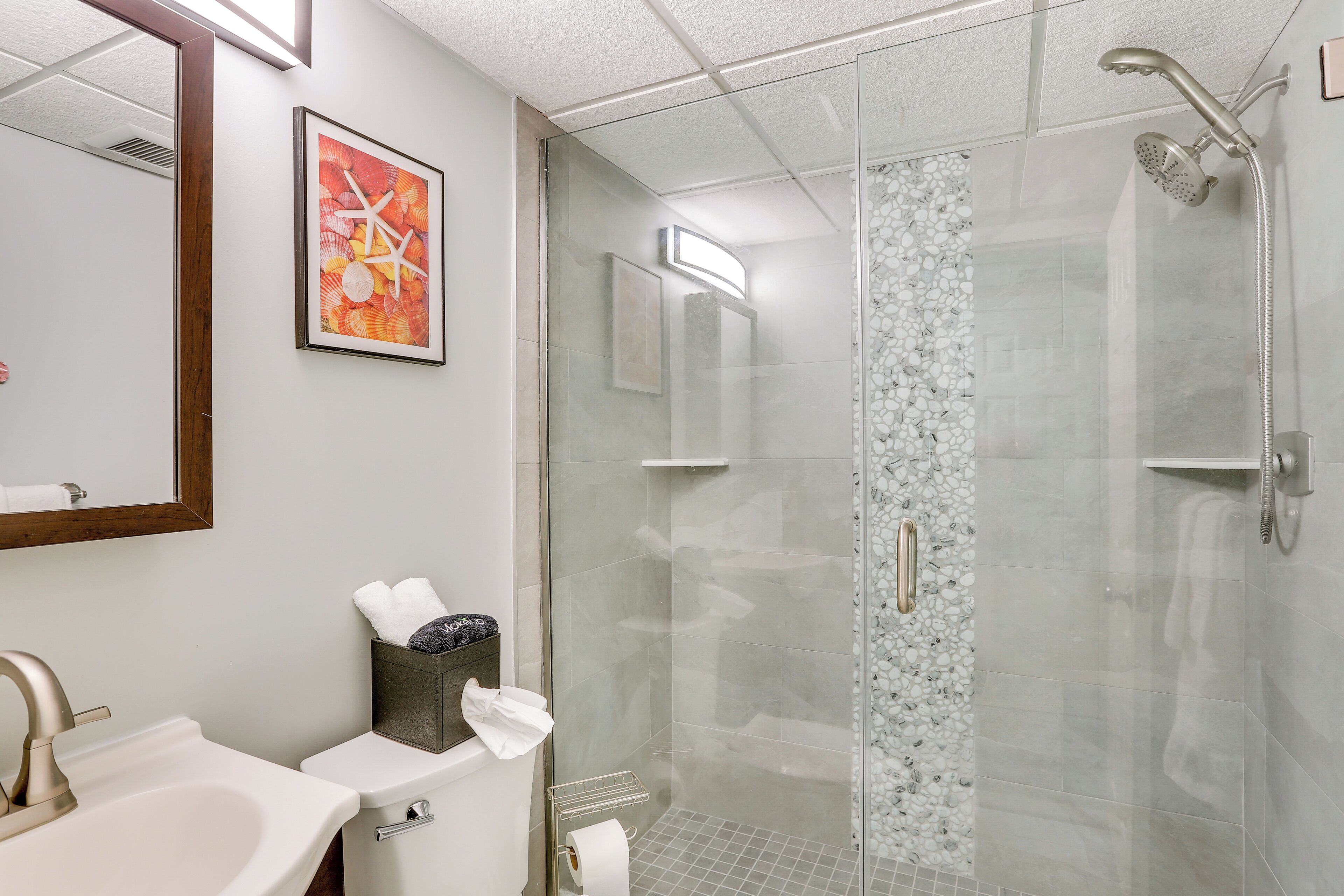 A modern bathroom with a glass shower enclosure, a sink, and a mirror.
