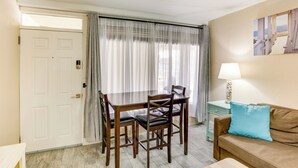 A room with a dining table and chairs, a sofa, a lamp, and a painting on the wall. - Wildwood Condo w/ Community Pool: Walk to Beach! (Wildwood)