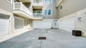 A multi-story residential building with a garage parking area, a small trash bin, and a door with a garage sign. - North Wildwood Townhome < 1/2 Mi to Beach! (North Wildwood)
