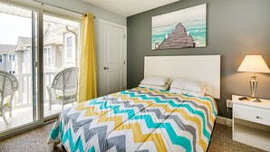 A bedroom with a bed, a nightstand, a lamp, a window with curtains, a view of the outside, and a painting on the wall. - North Wildwood Townhome < 1/2 Mi to Beach! (North Wildwood)