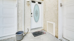 A white garage door with a decorative oval window, a welcome mat, and a light fixture above the door. - North Wildwood Townhome < 1/2 Mi to Beach! (North Wildwood)