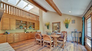 Une cuisine spacieuse dotée de meubles en bois, d’une table à manger et de chaises. Un escalier avec des rampes en bois mène à l’étage supérieur.